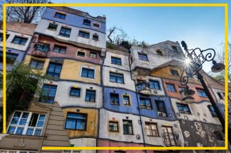 Bunte, unregelmäßig gestaltete Fassade des Hundertwasserhauses in Wien mit farbenfrohen Flächen, schiefen Linien, begrünten Bereichen und kleinen Balkonen unter blauem Himmel.