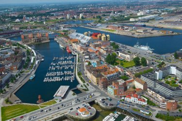 Luftaufnahme: Industriegebäude, Wohn- und Bürohäuser umgeben einen Hafen.