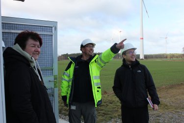 Drei Personen diskutieren vor Ort über den Windpark