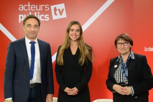 Drei Menschen vor einem roten Hintergrund, in der Mitte Sarah Bronsard