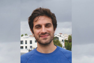 Person mit kurzen dunklen Haaren und blauem Pullover